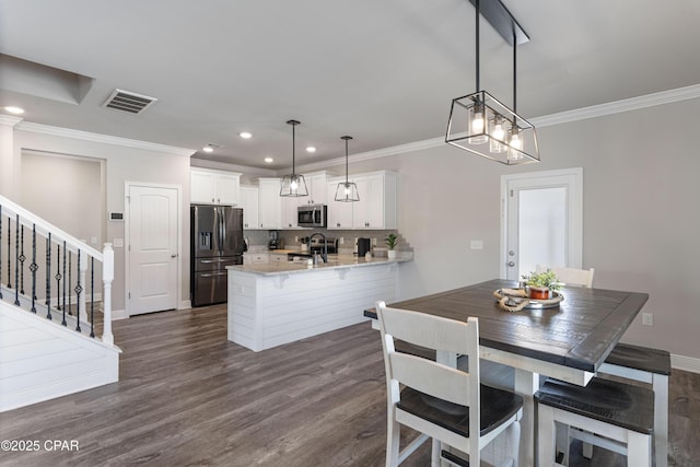 kitchen featuring a breakfast bar area, a peninsula, stainless steel appliances, white cabinetry, and pendant lighting