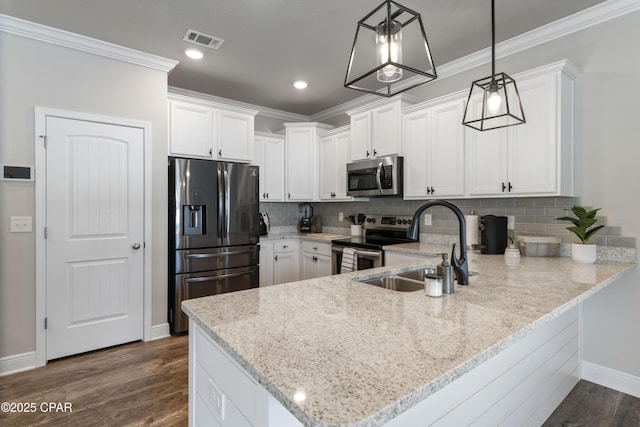 kitchen with hanging light fixtures, a peninsula, appliances with stainless steel finishes, and white cabinets