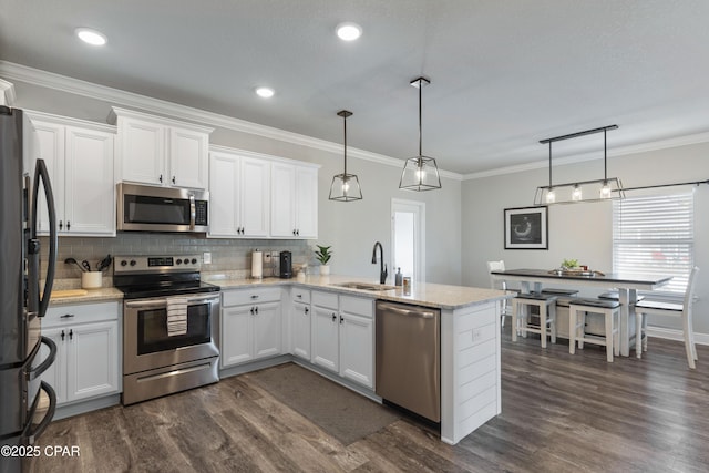 kitchen with stainless steel appliances, white cabinetry, hanging light fixtures, and a sink