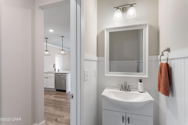 bathroom featuring wainscoting, crown molding, vanity, and wood finished floors