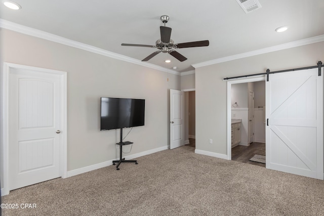 unfurnished bedroom featuring a barn door, visible vents, baseboards, crown molding, and carpet floors