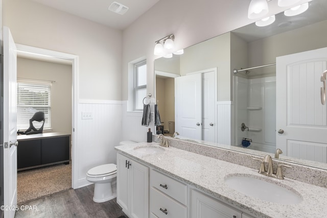 bathroom with a wainscoted wall, visible vents, a sink, and wood finished floors