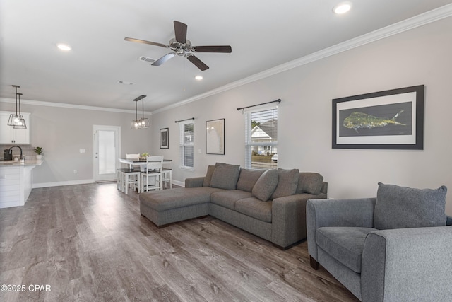 living room with recessed lighting, visible vents, ornamental molding, wood finished floors, and baseboards