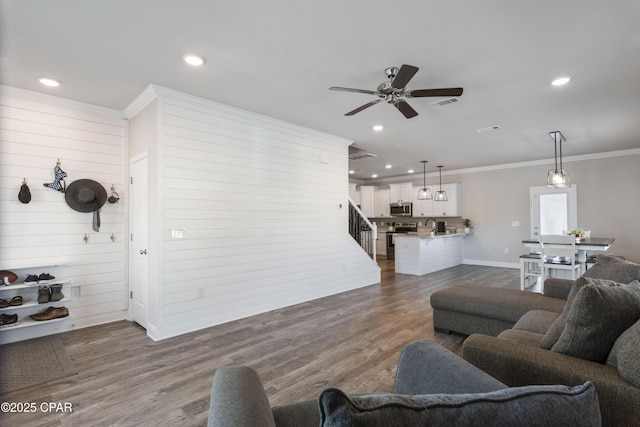 living area with recessed lighting, wood finished floors, visible vents, baseboards, and crown molding