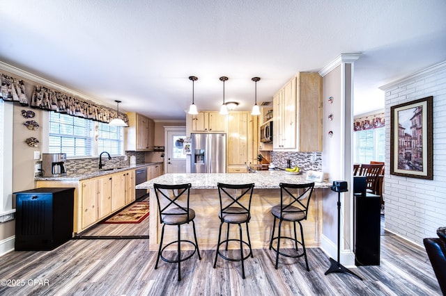 kitchen featuring pendant lighting, stainless steel appliances, and light brown cabinets