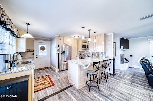 kitchen with stainless steel appliances, a breakfast bar, kitchen peninsula, and decorative light fixtures