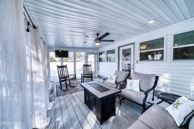 wooden terrace featuring ceiling fan and a fire pit