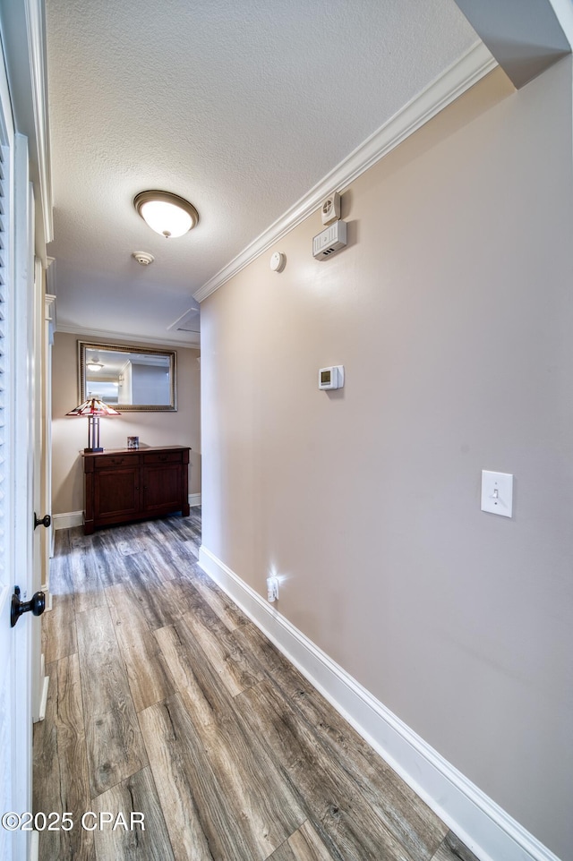 corridor with crown molding, hardwood / wood-style floors, and a textured ceiling