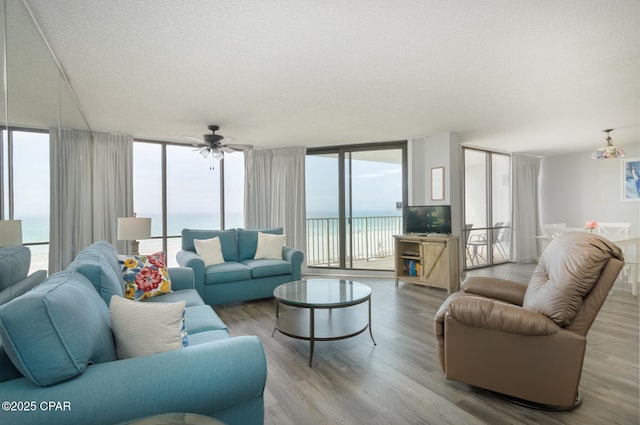 living room featuring floor to ceiling windows, a textured ceiling, ceiling fan, and wood finished floors