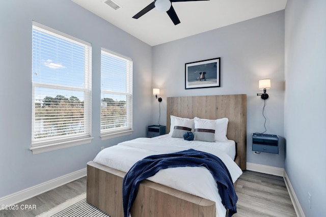 bedroom with light wood-style flooring, visible vents, baseboards, and a ceiling fan