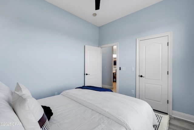 bedroom with a ceiling fan, baseboards, and wood finished floors