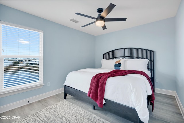 bedroom featuring a ceiling fan, baseboards, visible vents, and wood finished floors