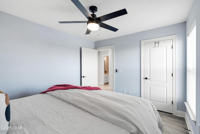 bedroom featuring ceiling fan, light wood-style flooring, and baseboards