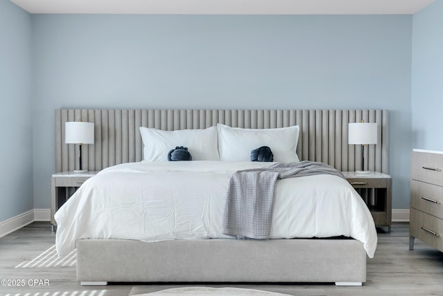 bedroom featuring light wood finished floors and baseboards