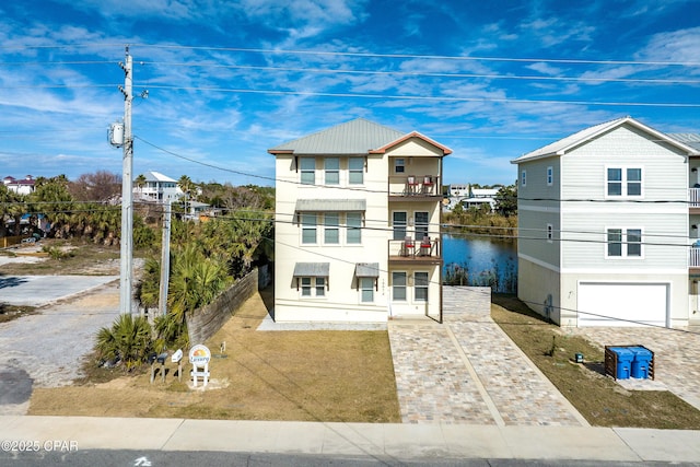 view of front of house featuring a balcony, a garage, and decorative driveway