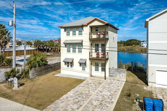 rear view of property featuring a yard, stucco siding, a water view, fence, and a balcony