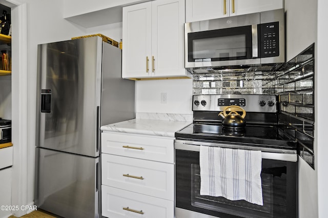 kitchen with light stone counters, stainless steel appliances, and white cabinets