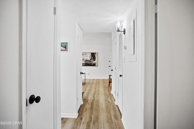 hallway featuring light hardwood / wood-style floors and a textured ceiling