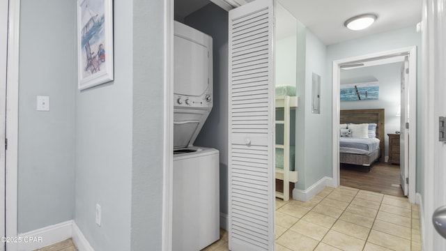 laundry room with light tile patterned flooring and stacked washer / dryer