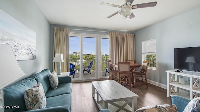 living room with dark wood-type flooring, ceiling fan, and a wealth of natural light