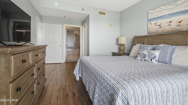 bedroom with ensuite bathroom and dark wood-type flooring