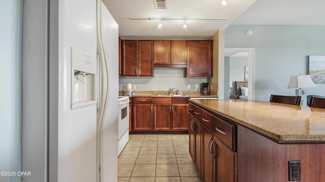 kitchen with light tile patterned flooring, a breakfast bar area, a center island, white appliances, and light stone countertops