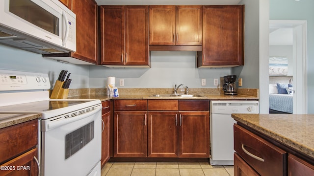 kitchen with light tile patterned flooring, white appliances, sink, and light stone counters