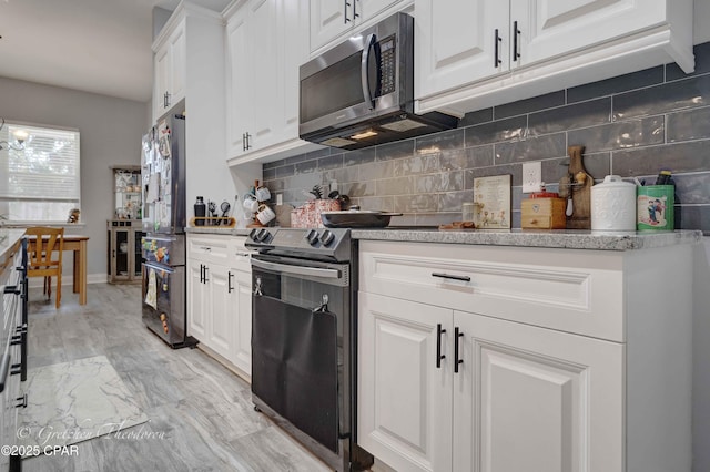 kitchen featuring stainless steel appliances, white cabinets, and backsplash