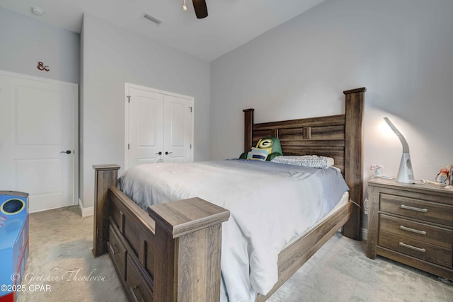 bedroom featuring light colored carpet, ceiling fan, and a closet