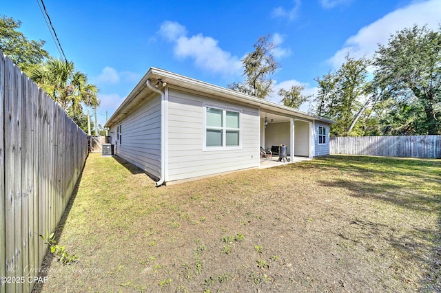 rear view of property featuring cooling unit, a yard, and a patio