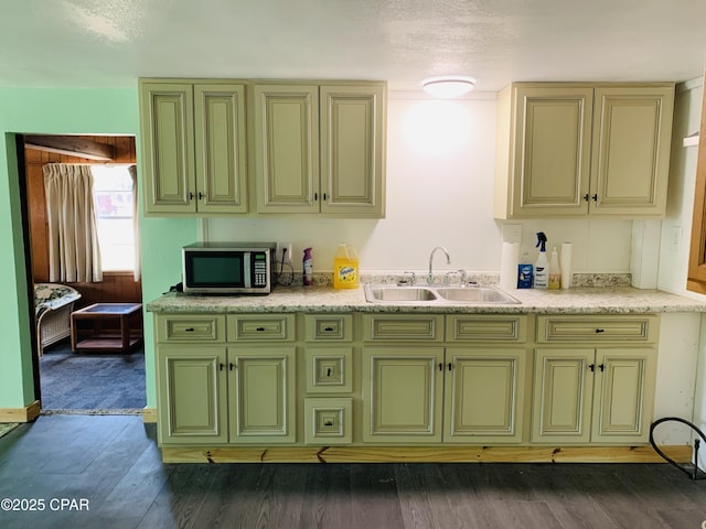 kitchen with dark wood-style floors, light countertops, stainless steel microwave, and a sink