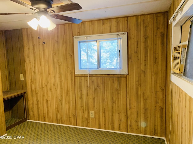 unfurnished room with carpet, ceiling fan, wooden walls, and baseboards