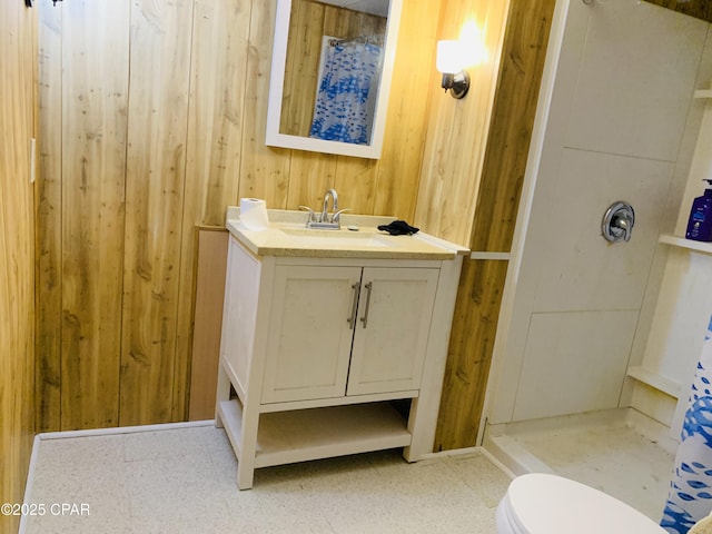 bathroom featuring toilet, wood walls, vanity, tile patterned floors, and walk in shower