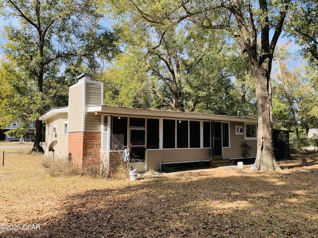 back of house with entry steps, a chimney, and brick siding