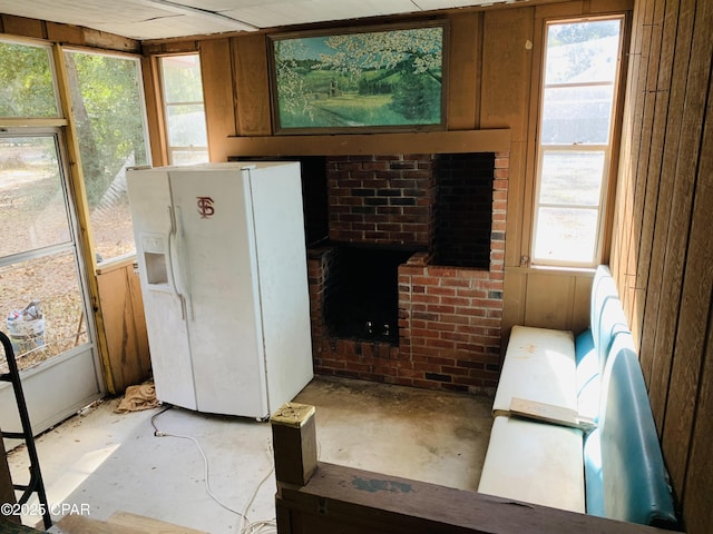 kitchen with a healthy amount of sunlight, white refrigerator with ice dispenser, brown cabinetry, and concrete flooring