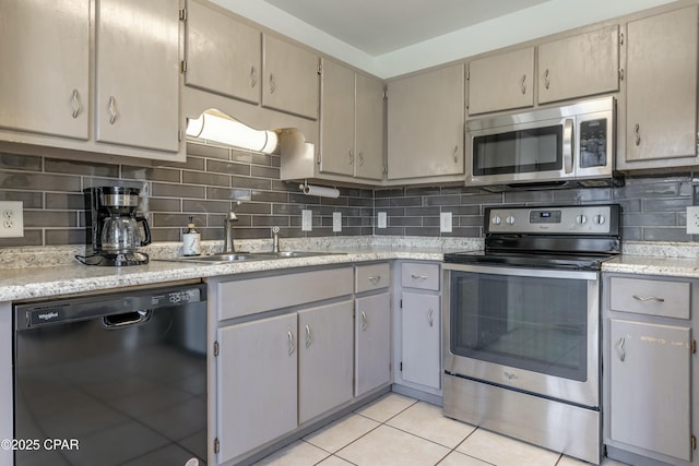 kitchen featuring light tile patterned flooring, a sink, stainless steel appliances, light countertops, and backsplash