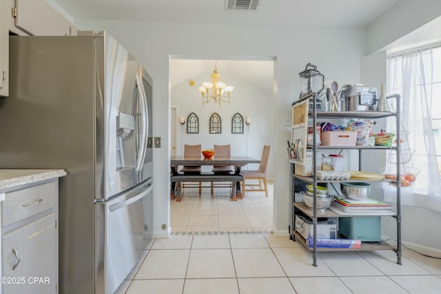 kitchen with baseboards, vaulted ceiling, light tile patterned floors, stainless steel refrigerator with ice dispenser, and a notable chandelier