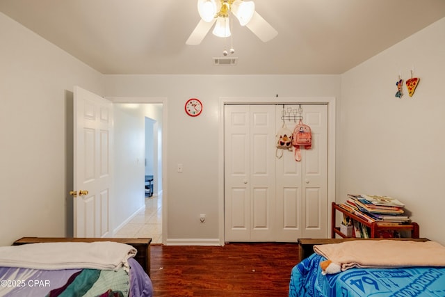 bedroom with wood finished floors, visible vents, baseboards, ceiling fan, and a closet