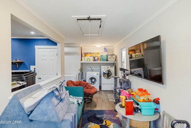 clothes washing area with wood finished floors, a wall mounted AC, laundry area, attic access, and washing machine and dryer