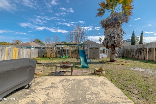 view of yard with a patio, an outbuilding, an outdoor fire pit, a fenced backyard, and a storage shed