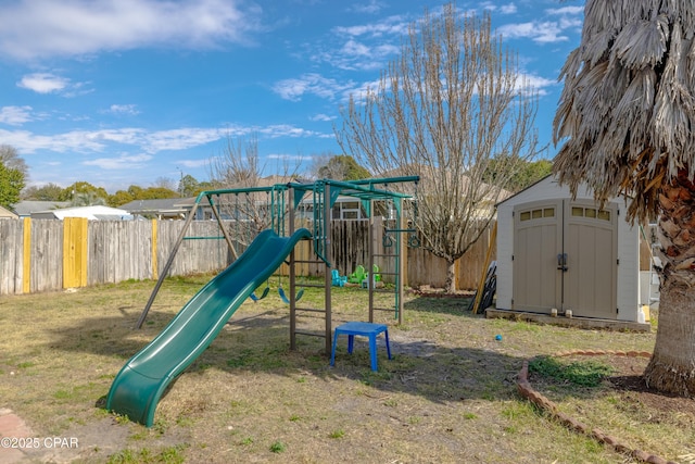 view of playground with an outbuilding, a lawn, a storage shed, and fence