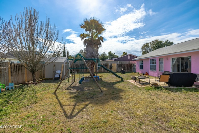 view of yard featuring an outbuilding, a playground, a fenced backyard, and a shed