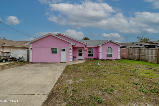 ranch-style home featuring a front yard, concrete driveway, fence, and stucco siding