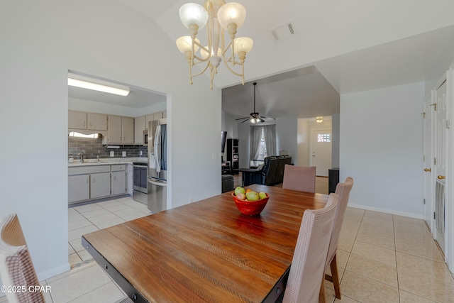 dining space with visible vents, ceiling fan with notable chandelier, light tile patterned floors, baseboards, and vaulted ceiling