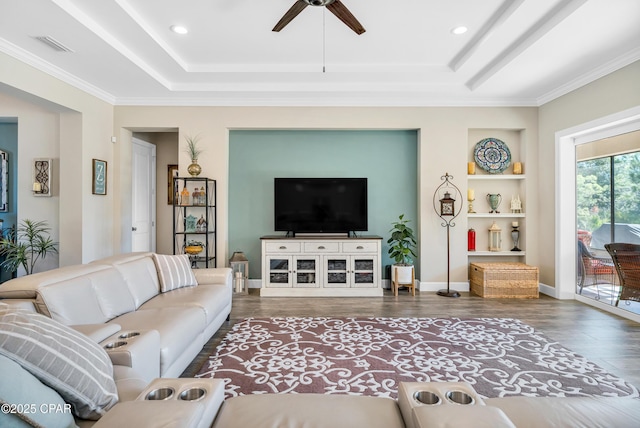 living area featuring built in features, a raised ceiling, baseboards, and wood finished floors