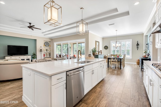 kitchen with wood finished floors, a sink, open floor plan, dishwasher, and crown molding