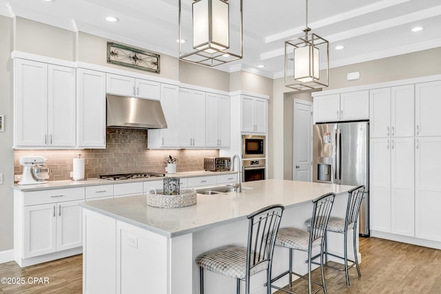 kitchen with light wood-style flooring, appliances with stainless steel finishes, white cabinetry, a sink, and under cabinet range hood