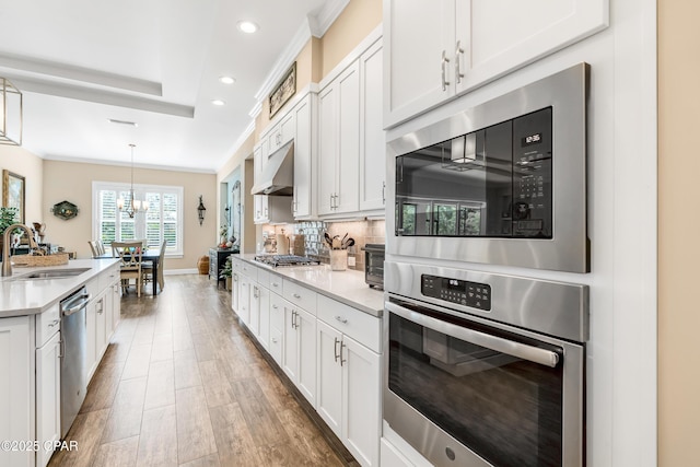 kitchen with crown molding, light countertops, decorative backsplash, appliances with stainless steel finishes, and a sink