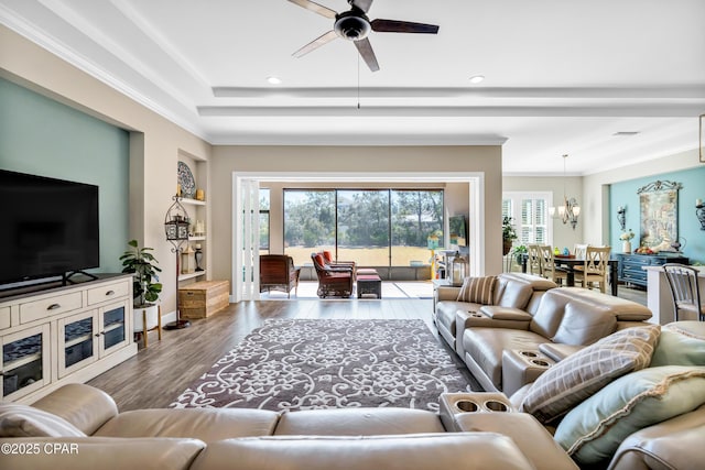 living area featuring ceiling fan with notable chandelier, a raised ceiling, plenty of natural light, and wood finished floors