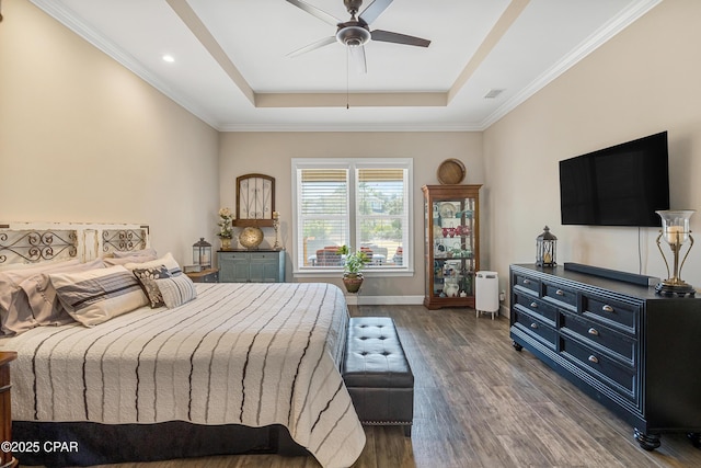 bedroom with a tray ceiling, dark wood-style flooring, visible vents, and baseboards